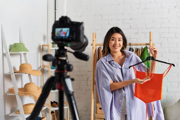 Creative asian stylist showing crop top and accessories during fashion vlog in private atelier — Stock Photo