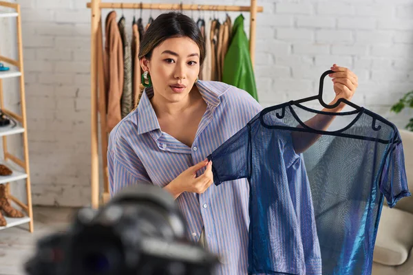 Талановитий молодий азіатський дресмейкер, що демонструє модну блузку під час відеоблогу в модній студії — стокове фото