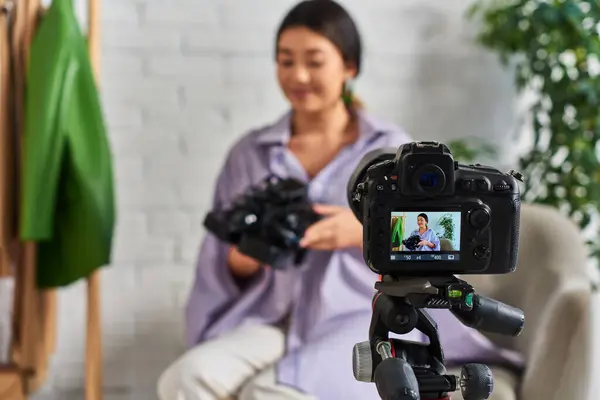 Foco na câmera digital perto talentoso asiático estilista com roupas na moda no atelier, moda vlog — Fotografia de Stock
