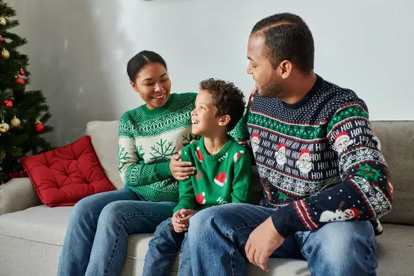 Joyeuse famille afro-américaine en chandails d'hiver assis sur le canapé se souriant, Noël — Photo de stock