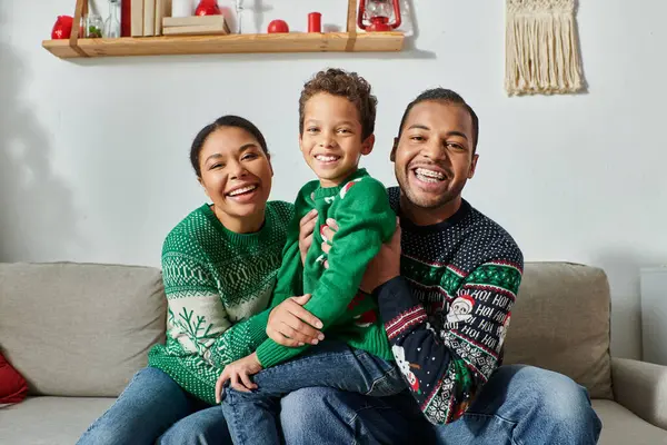 Bien parecido afroamericano familia posando juntos y sonriendo alegremente a la cámara, Navidad - foto de stock