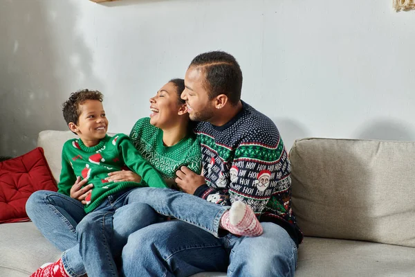 Freudige afrikanisch-amerikanische Eltern halten ihren Sohn auf dem Schoß und lächeln einander fröhlich zu, Weihnachten — Stockfoto