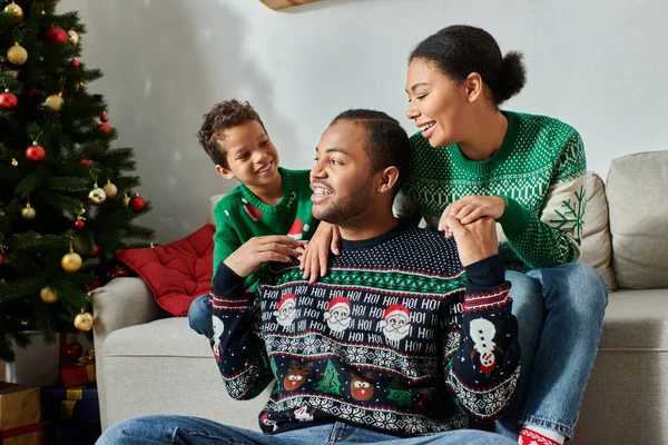 Felice famiglia afroamericana con bambino sorridente e indossa maglioni casual caldi, Natale — Foto stock