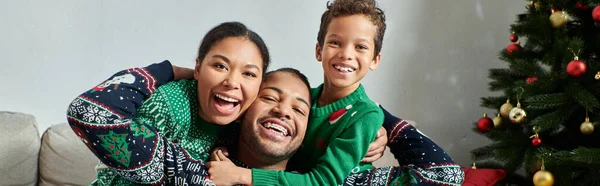 Fröhliche afrikanisch-amerikanische Familie in Pullovern, die sich warm umarmen und in die Kamera lächeln, Weihnachten, Banner — Stockfoto