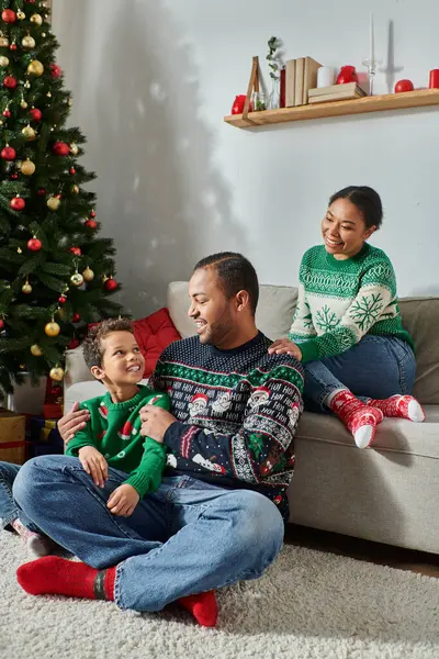 Tiro vertical de la mujer afroamericana mirando a su marido cosquillas a su hijo, Navidad - foto de stock