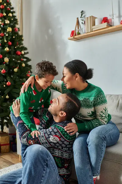 Tiro vertical de alegre família afro-americana em camisolas casuais sorrindo um para o outro, Natal — Fotografia de Stock