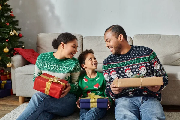 Joyous african american parents looking lovingly at their son and holding presents, Christmas — Stock Photo