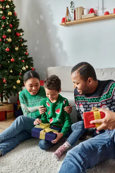 Plan vertical de heureux parents afro-américains aimants donnant des cadeaux de Noël à leur fils — Photo de stock