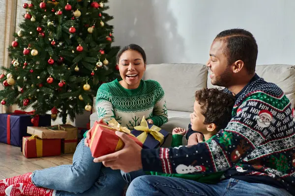 Happy beautiful family in warm sweaters exchanging presents and smiling joyfully, Christmas — Stock Photo