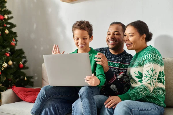 Happy african american family spending time together while son waving at laptop camera, Christmas — Stock Photo