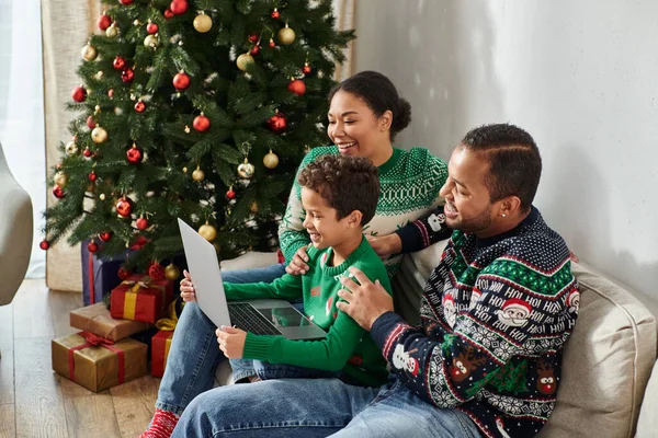 Heureux moderne afro-américain famille regarder film ensemble assis sur canapé à côté de l'arbre de Noël — Photo de stock
