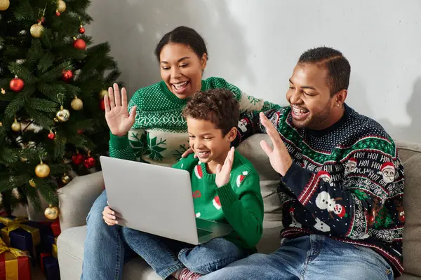 Joyeuse famille afro-américaine moderne dans des pulls confortables agitant salut à la caméra portable, Noël — Photo de stock