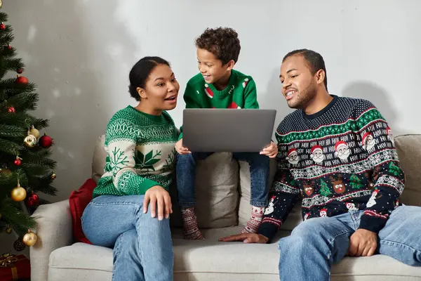 Joyous african american woman looking surprised watching Christmas movie with her son and husband — Stock Photo