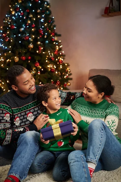 Tiro vertical de família americana africana alegre em camisolas aconchegantes sorrindo um para o outro, Natal — Fotografia de Stock