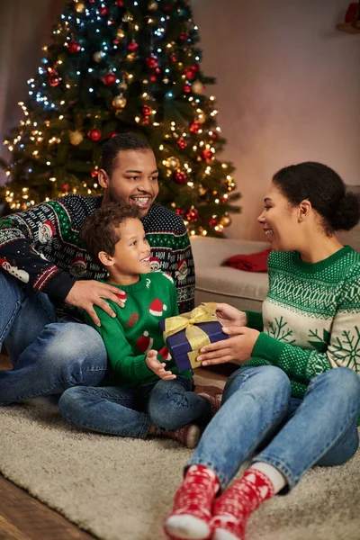 Vertical shot of happy african american woman giving present to her son and husband, Christmas — Stock Photo