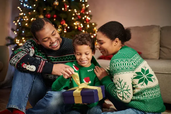 Freudige afrikanisch-amerikanische Familie lächelt und umarmt liebevoll neben Weihnachtsbaum mit Girlanden — Stockfoto