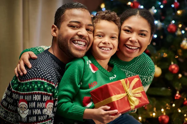 Portrait de heureuse famille afro-américaine souriant joyeusement à la caméra, présent dans les mains, Noël — Photo de stock