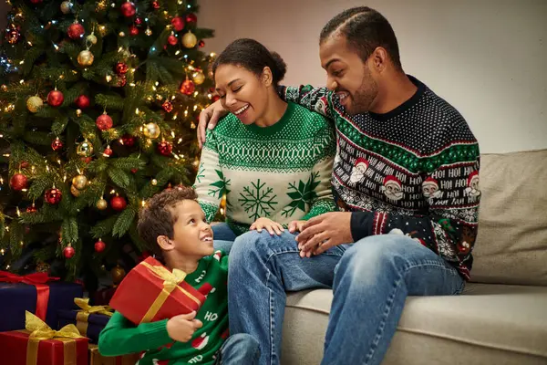 Familia afroamericana feliz pasar tiempo juntos intercambiar regalos en la noche de Navidad - foto de stock