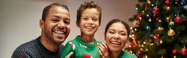 Moderne joyeuse famille afro-américaine souriant à la caméra avec arbre de Noël sur fond, bannière — Photo de stock