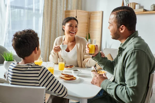 Cheerful modern african american family in casual outfits having breakfast together smiling joyfully — Stock Photo