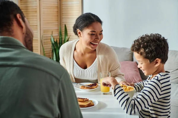 Focus on jolly african american woman looking at her son with blurred husband in front of them — Stock Photo