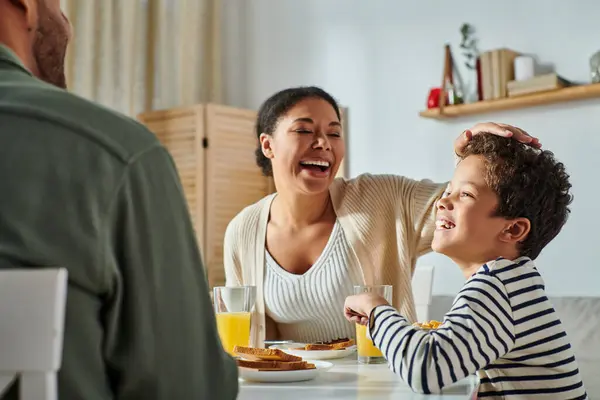 Vista recortada del hombre afroamericano sentado en la mesa de desayuno frente a su alegre esposa e hijo — Stock Photo