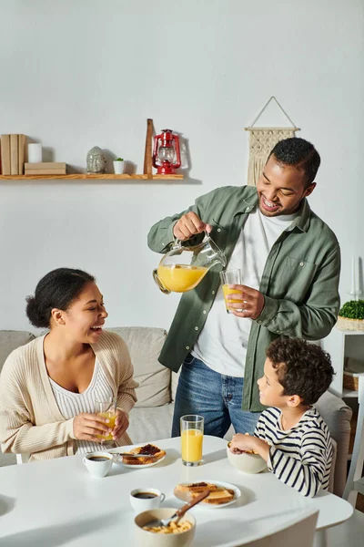 Vertical shot of modern african american family in casual home wear having breakfast together — Stock Photo