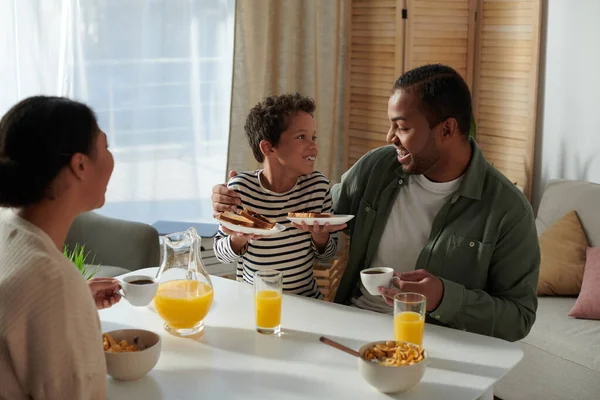Focus on jolly african american father and son smiling with blurred mother looking at them — Stock Photo
