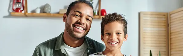 Feliz pai e filho afro-americano sentado à mesa do café da manhã e sorrindo para a câmera, banner — Fotografia de Stock