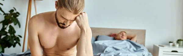 Sconvolto uomo gay barbuto seduto con la testa piegata vicino al partner dormire in camera da letto, banner orizzontale — Foto stock
