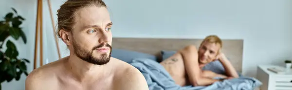 Sonhador e positivo barbudo homem olhando para longe perto gay parceiro deitado na cama, felicidade, banner — Fotografia de Stock
