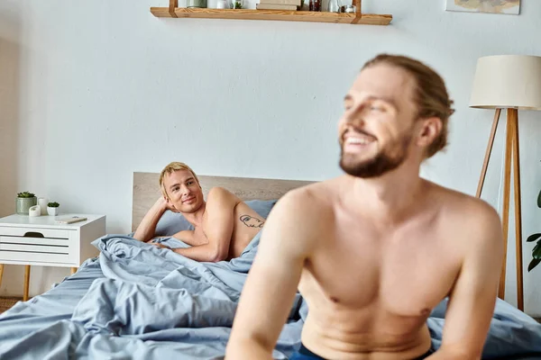 Allegro barbuto gay uomo guardando lontano vicino amore partner sdraiato in camera da letto, armonioso rapporto — Foto stock