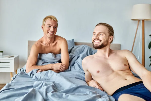 Весела гей-пара посміхається в затишній спальні вранці, задоволення і гармонійні відносини — стокове фото