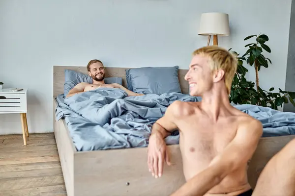 Joyeux barbu gay l'homme couché sur lit et regardant sourire copain le matin, heureux chambre scène — Photo de stock