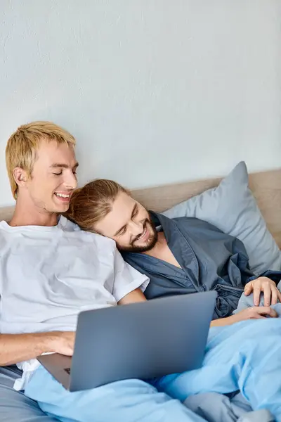 Sourire gay couple regarder romantique film sur portable dans chambre, heureux matin loisirs sur lit — Photo de stock