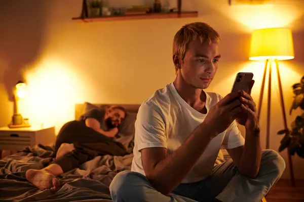 Unfaithful gay man chatting on mobile phone near love partner sleeping at night in bedroom — Stock Photo