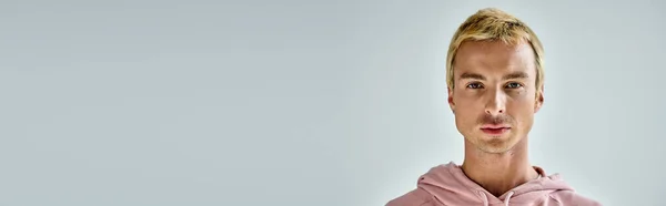 Ritratto di uomo carismatico con capelli biondi tinti guardando la macchina fotografica su sfondo grigio, banner — Foto stock