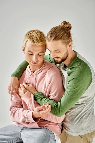 Romântico e sensual gay casal no elegante casual traje abraçando no cinza pano de fundo, gay amor — Fotografia de Stock