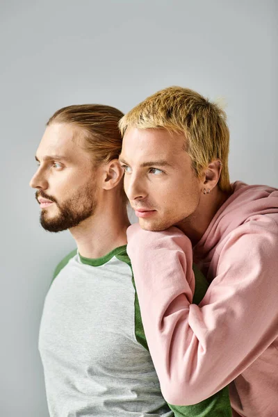 Romantique rêveur gay couple dans tendance casual tenue regardant loin sur gris toile de fond, harmonie et amour — Photo de stock