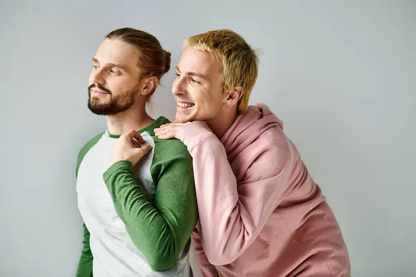 Feliz e sonhador gay casal na moda casual traje olhando afastado no cinza pano de fundo, harmonia e amor — Fotografia de Stock