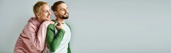 Sourire et rêveur gay couple à la mode casual tenue regardant loin sur fond gris, bannière — Photo de stock