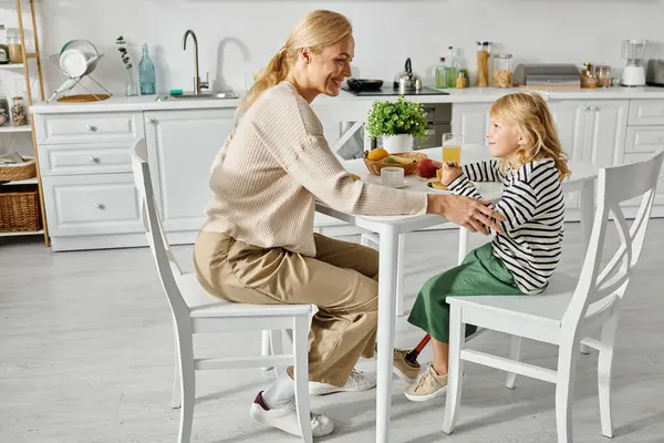 Glückliche Mutter frühstückt mit ihrer kleinen Tochter mit Beinprothese in der Küche, Inklusion — Stockfoto
