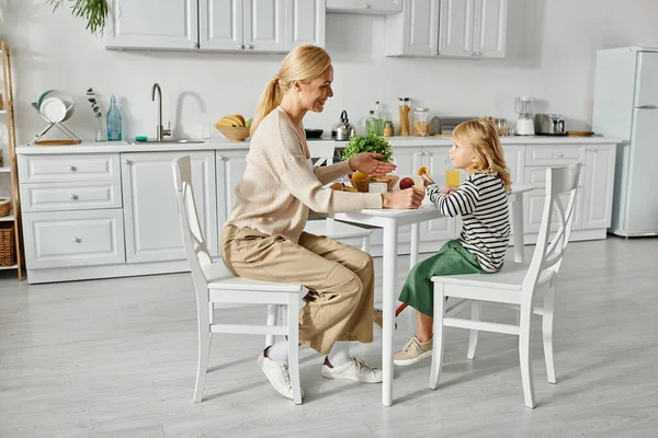 Glückliche Mutter frühstückt mit ihrer kleinen Tochter mit Beinprothese in der Küche, Inklusion — Stockfoto