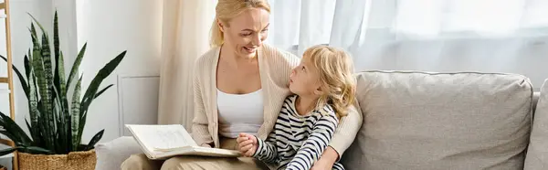 Mãe feliz ler livro para a filha loira enquanto sentados juntos na sala de estar moderna, banner — Fotografia de Stock