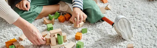 Cropped banner, girl with prosthetic leg sitting on carpet and playing with wooden toys near mother — Stock Photo