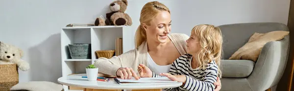 Счастливая блондинка смотрит на свою дочь, рисующую на бумаге цветным карандашом, горизонтальным баннером — стоковое фото