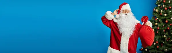 Emocionado Santa Claus con barba y anteojos sosteniendo saco bolsa con regalos de Navidad, pancarta - foto de stock