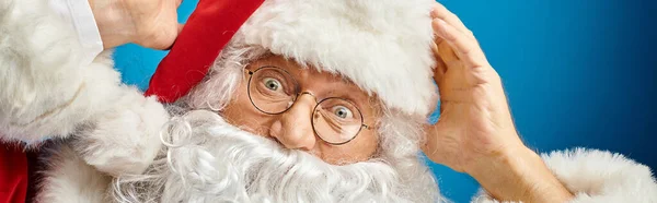 Retrato de Papai Noel animado com barba branca e óculos olhando para a câmera em azul, banner — Fotografia de Stock
