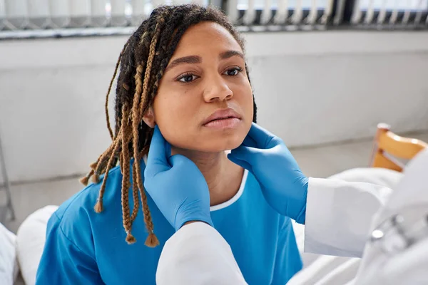 Giovane donna afro-americana guardando il suo medico indiano mentre esaminava i suoi linfonodi — Foto stock