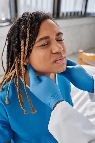 Giovane medico indiano che esamina i linfonodi della sua malata paziente afro-americana, assistenza sanitaria — Foto stock